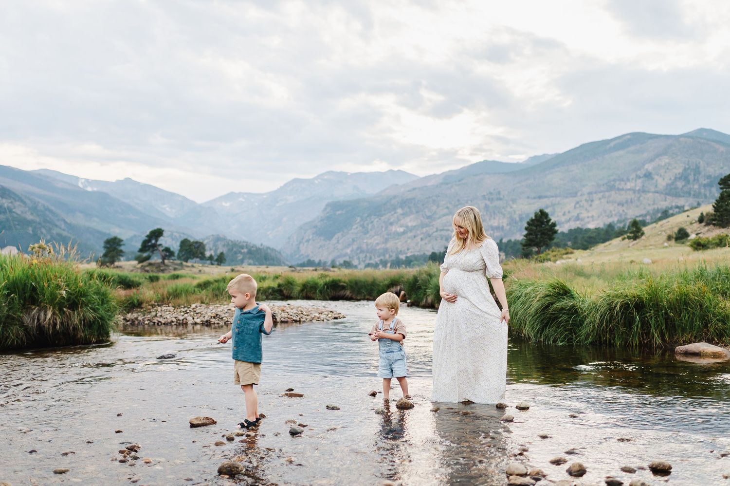 Maternity photo session in the creek of Rocky Mountain national park. Estes park maternity session. Mom and sons posing in a creek w