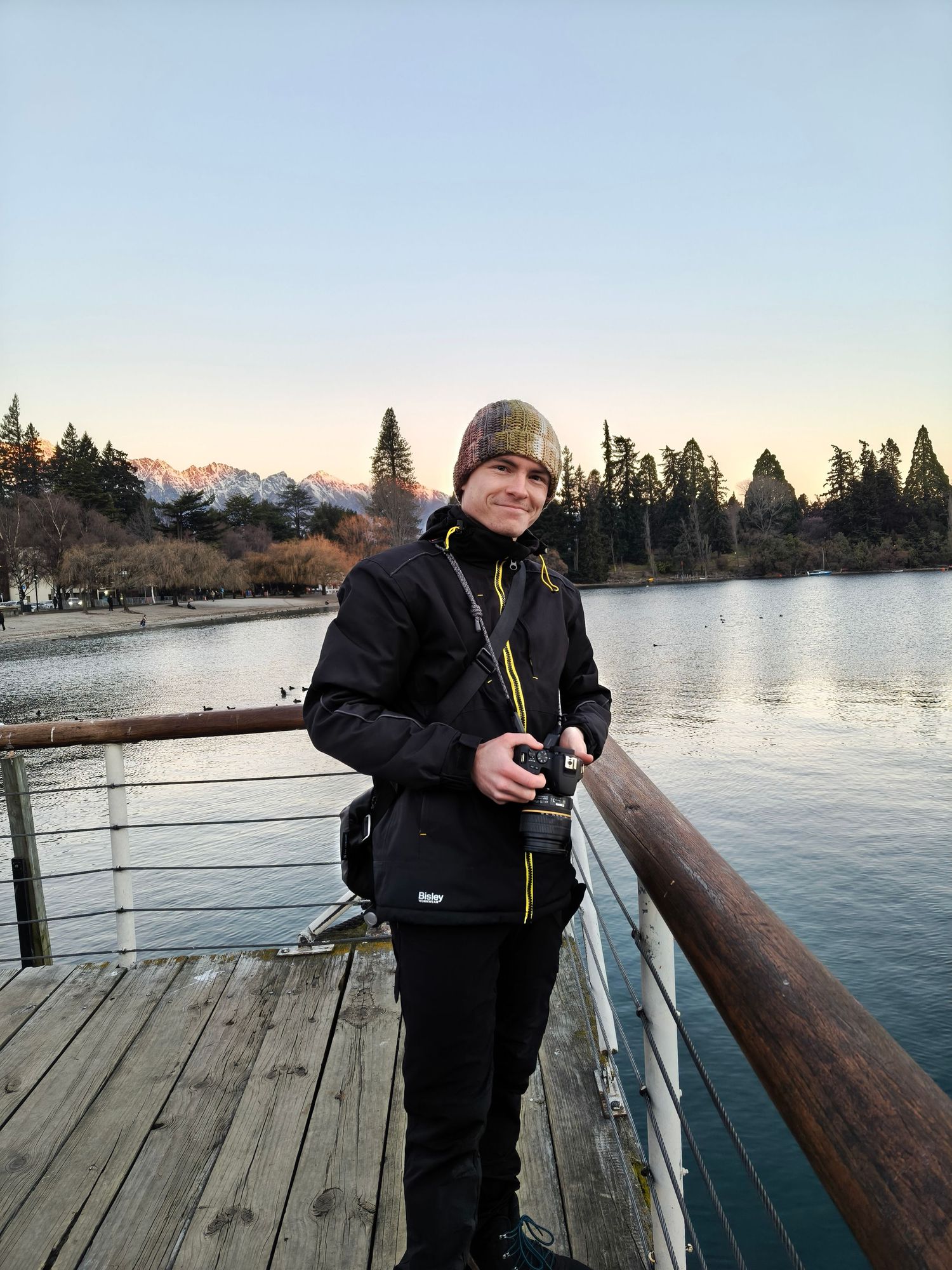 Locky B Photography self-portrait, photographer holding his camera and smiling in Queenstown, New Zealand.