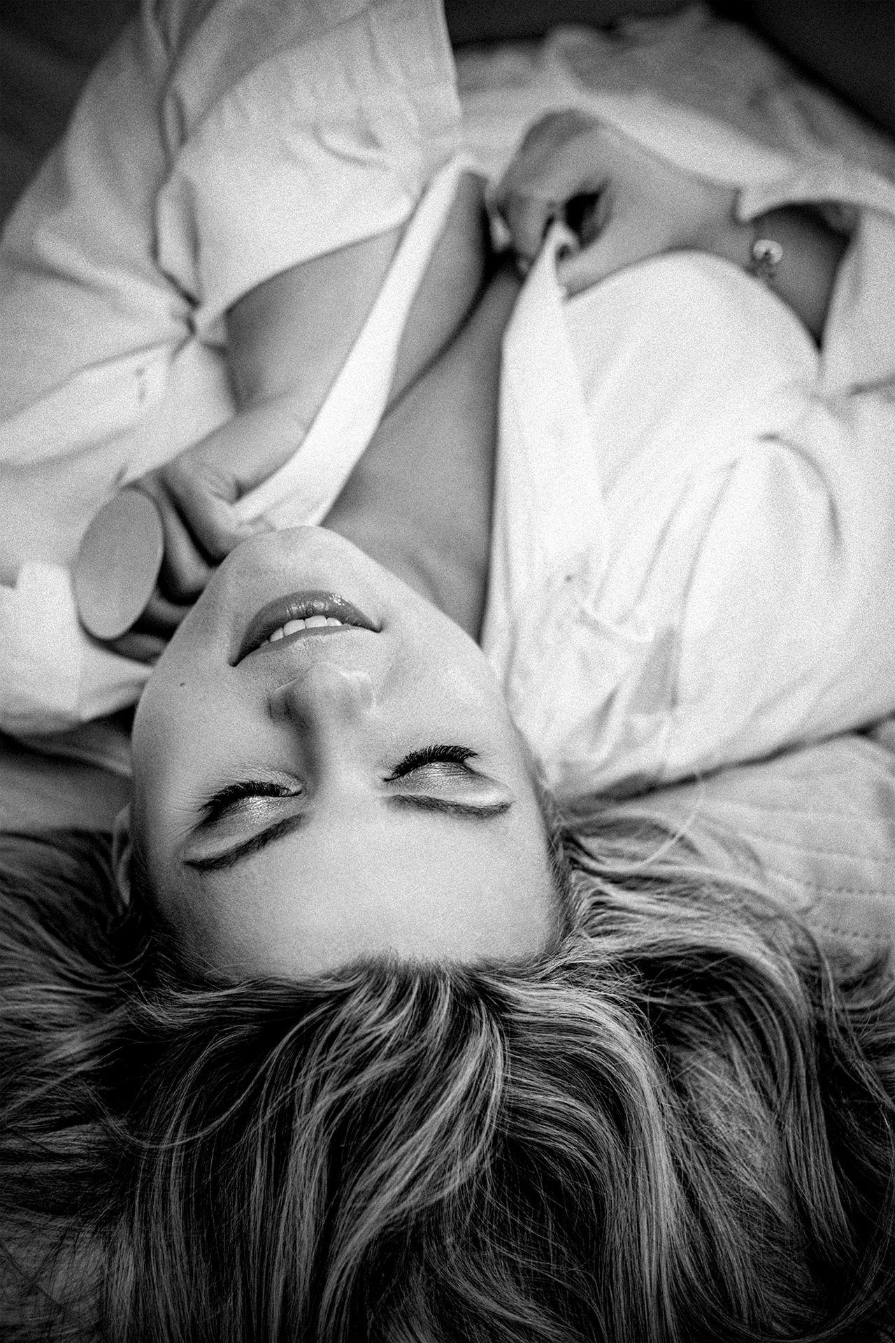 Fine art black and white portrait of a woman lying on a bed by Martyna Osuchowska