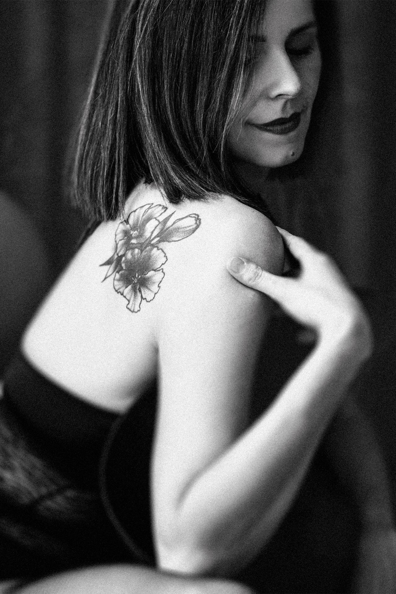 Artistic black and white boudoir portrait highlighting a floral shoulder tattoo