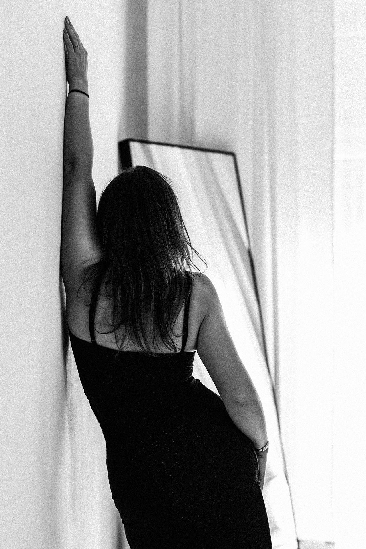 Black and white fine art portrait of a woman standing beside a mirror. Elegant women's portrait photography by Martyna Osuchowska, Częstocho