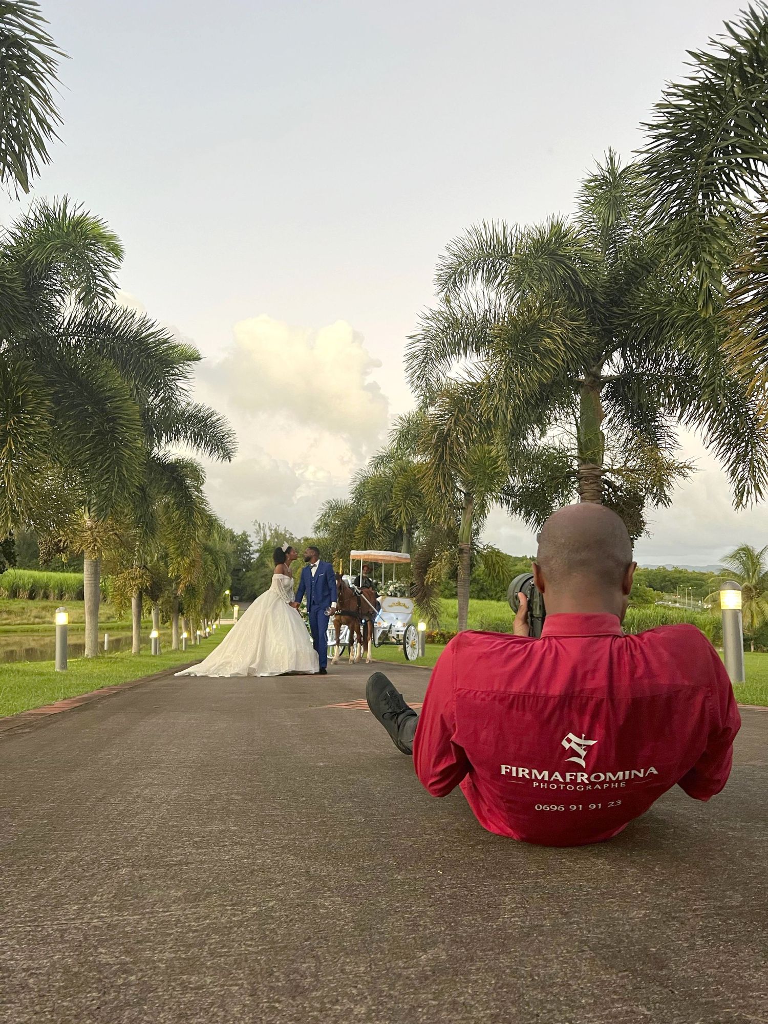 Photographe couché au sol prenant les mariés dans la grande allée de l'habitation Vatable en Martinique