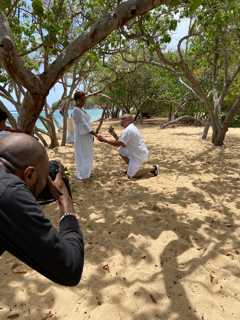 Scène au bord de la plage de Trinité en Martinique de mariés qui renouvellent leurs voeux, l'homme ayant un genou dans le sable