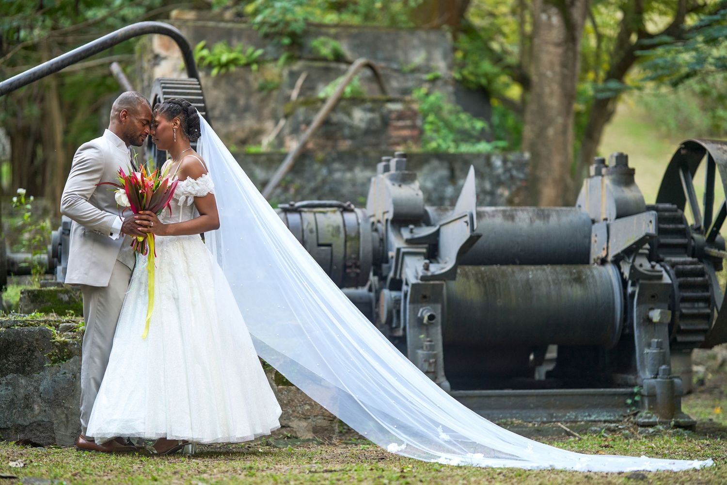 Couple marié enlacé devant des anciennes machines de l'habitation La Sucrerie aux Anses d'Arlet en Martinique