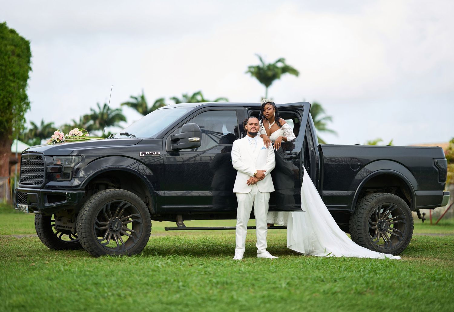 Mariés posant devant un pick-up noir, mise en scène de mariage Habitation Laguerre Martinique