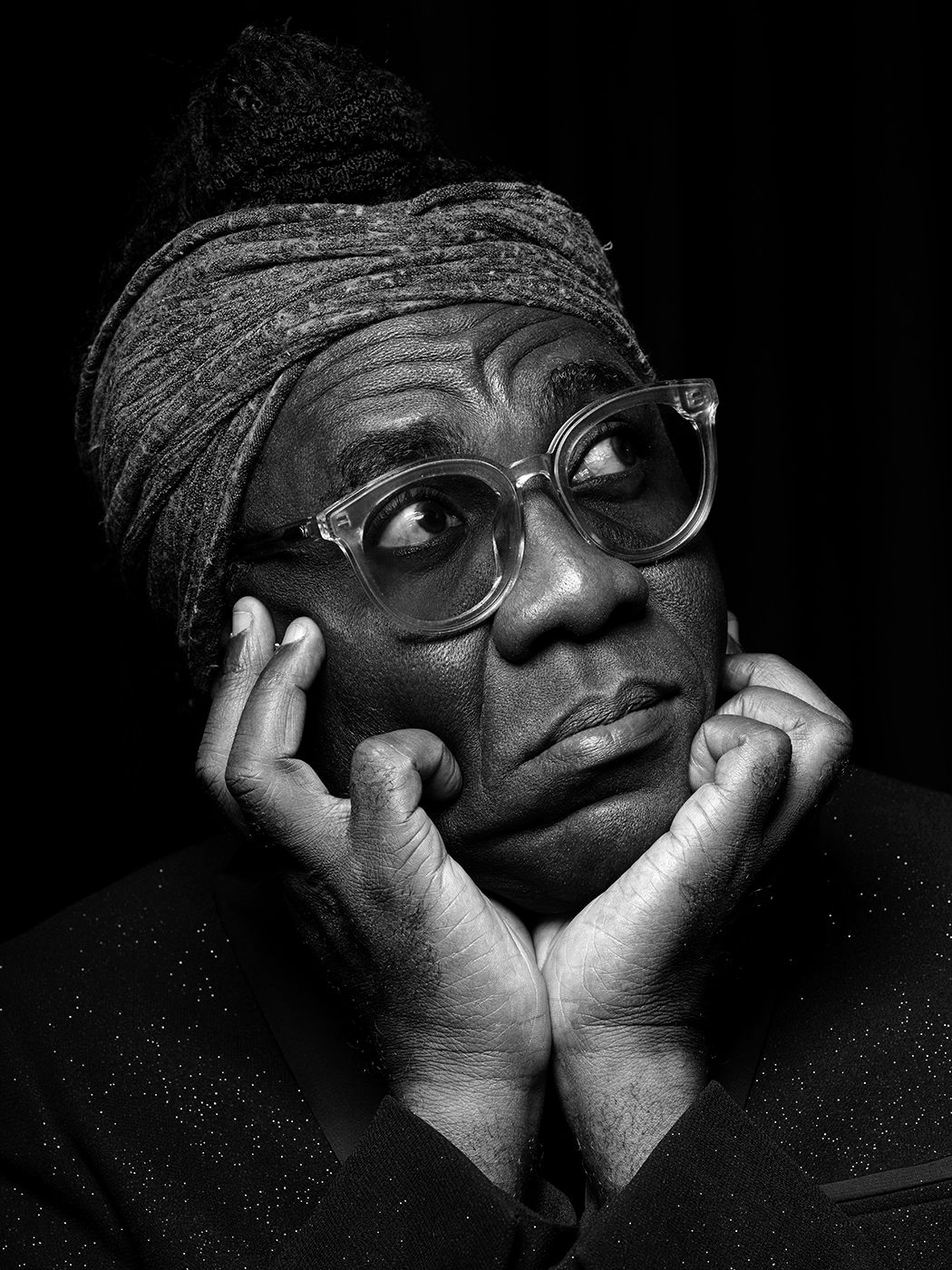 Black and white portrait of an elderly woman wearing glasses and a head wrap, resting her chin on her hands. Richard Bona, musician, bass.