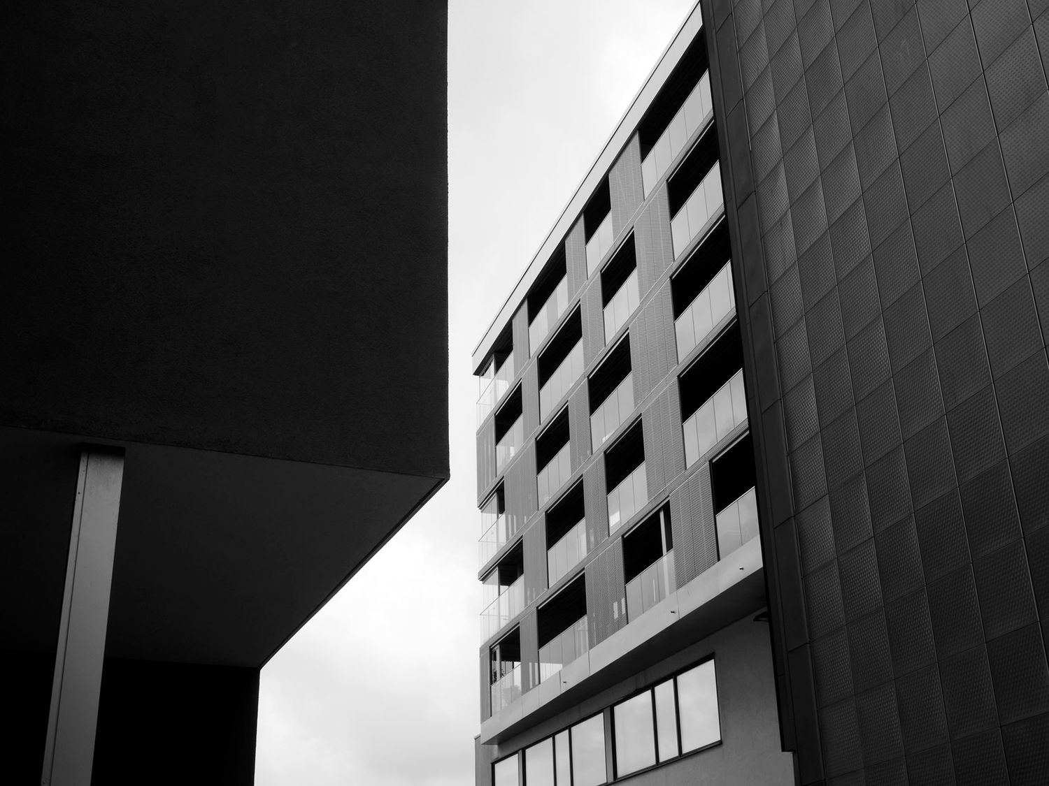 Black and white architectural photo of modern buildings with geometric patterns against an overcast sky.
