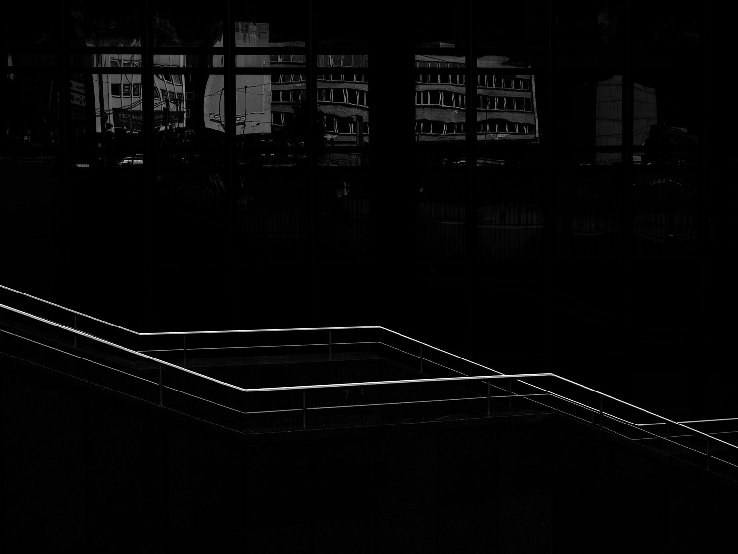 Dark urban night scene with glowing white geometric lines outlining steps near a modern building.