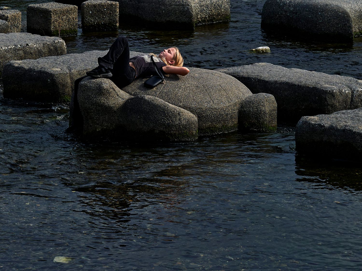 Person relaxing on large stepping stones surrounded by calm water at the Giant's Causeway, Northern Ireland.