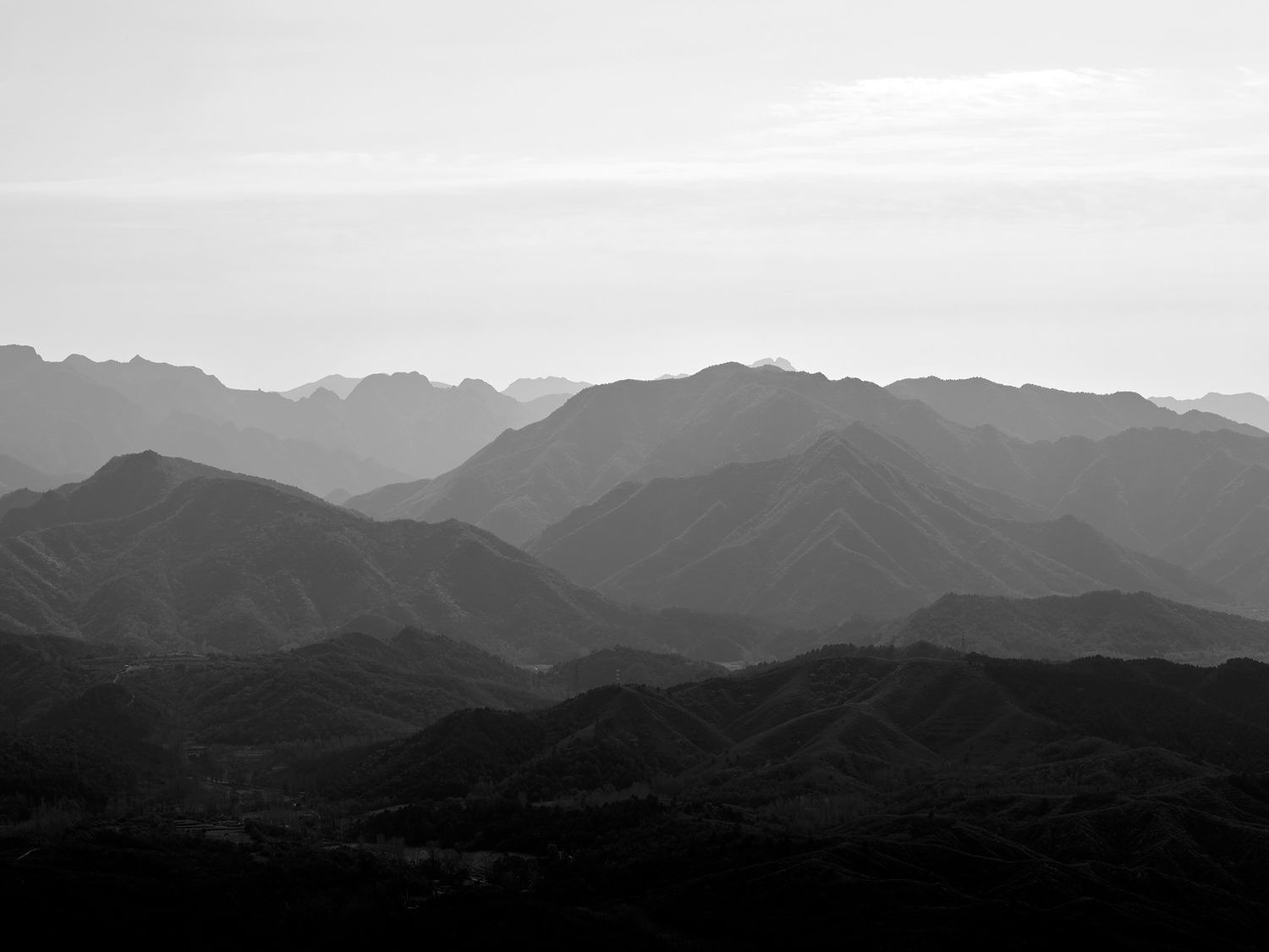 Black and white landscape photo of layered mountain ranges receding into a misty horizon.
