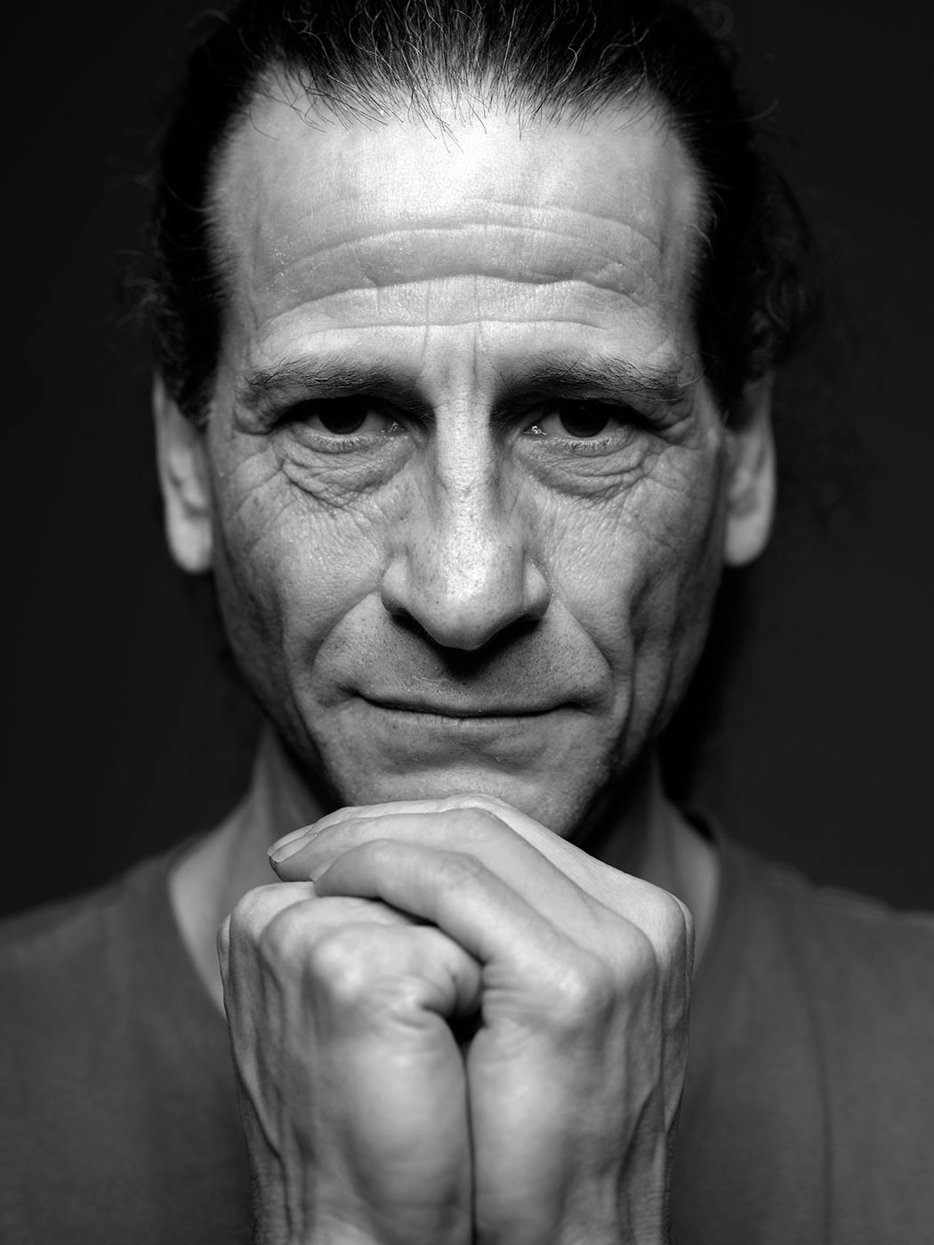 Black and white portrait of a middle-aged man with clasped hands resting under his chin. Pettik Ádám