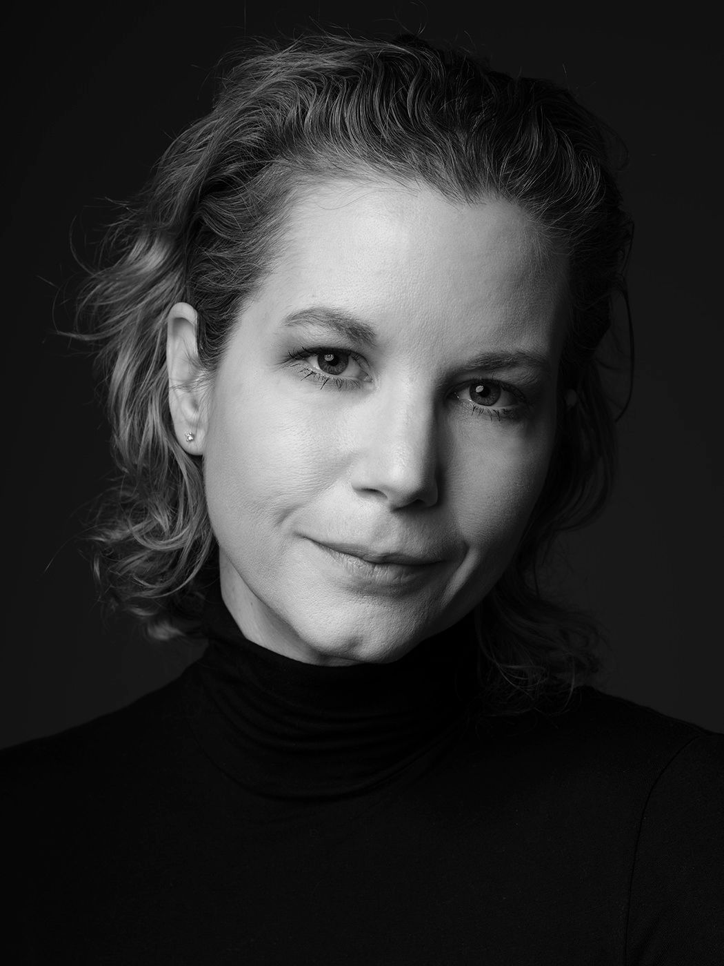 Black and white portrait of a woman with curly hair wearing a turtleneck, professional headshot photography. Kézdy Luca