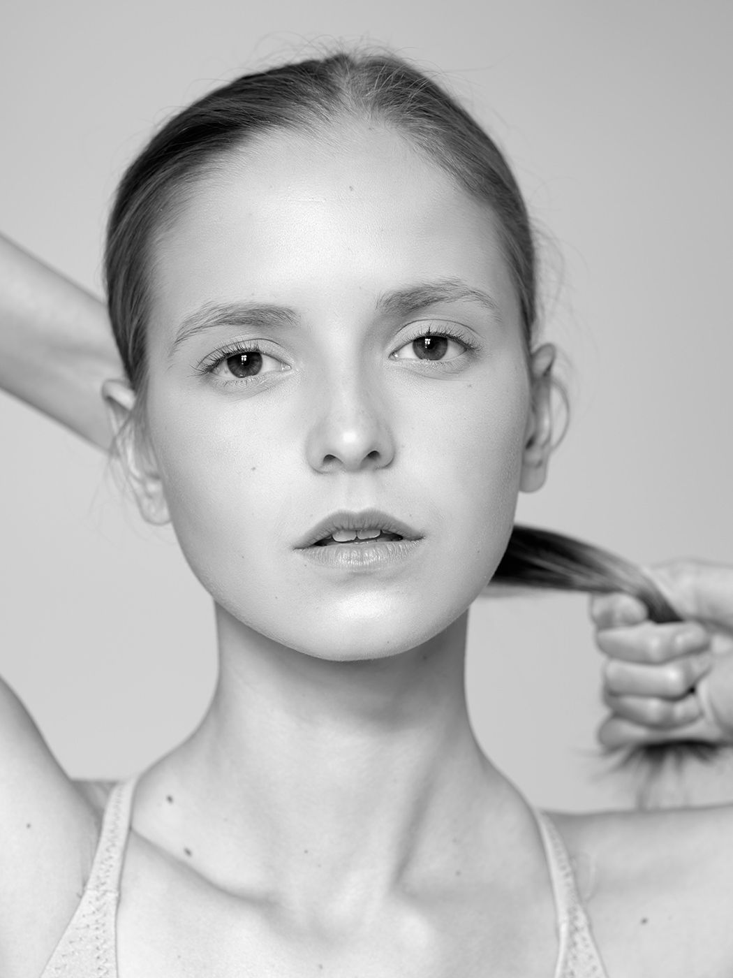 Black and white portrait of a young woman with braided hair pulled back, wearing a white top.