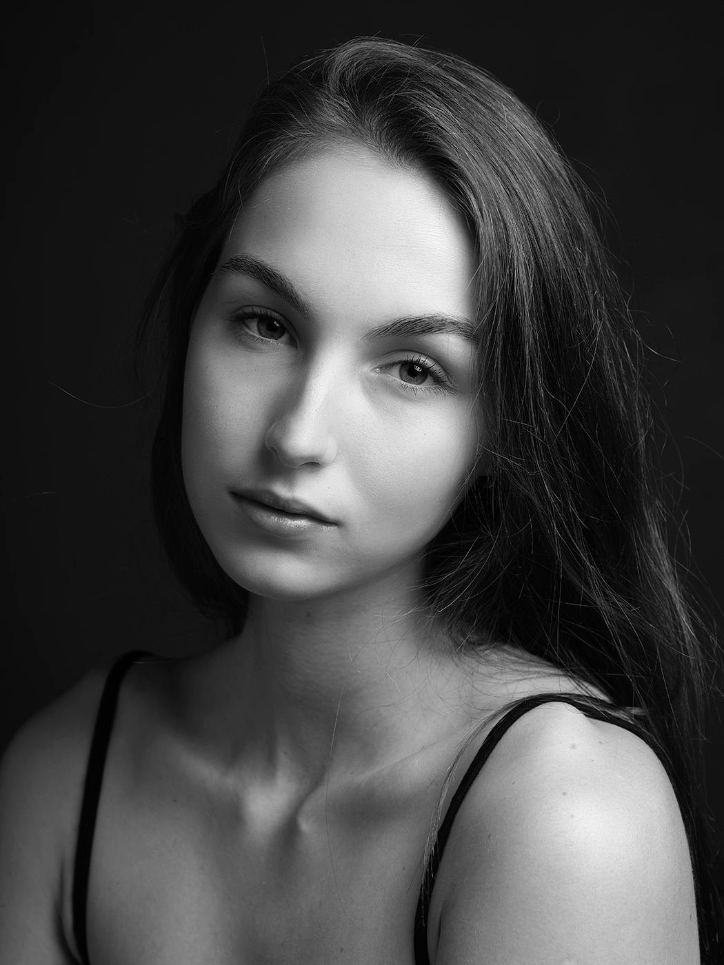 Black and white portrait of a young woman with long dark hair, looking directly at the camera.