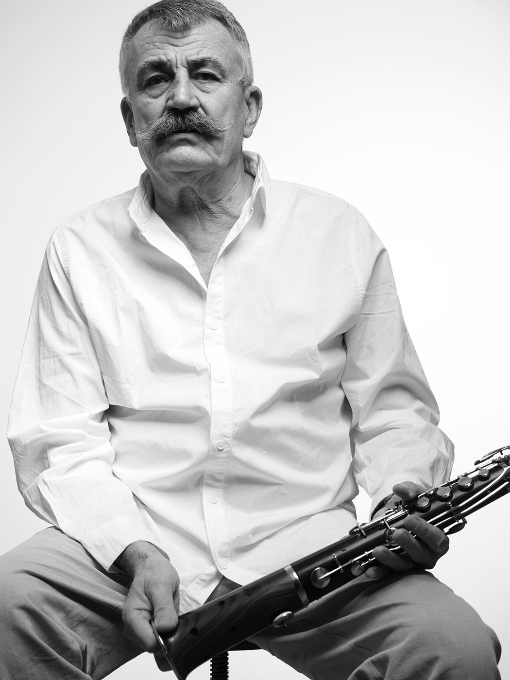 Black and white portrait of an older man with a mustache holding a clarinet, wearing a white shirt. Dresch Mihály