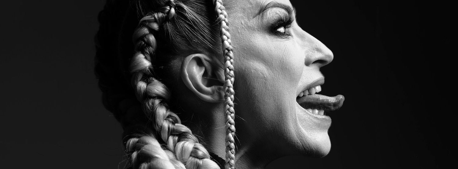 Black and white profile portrait of a woman with long braided hair, laughing with mouth open.