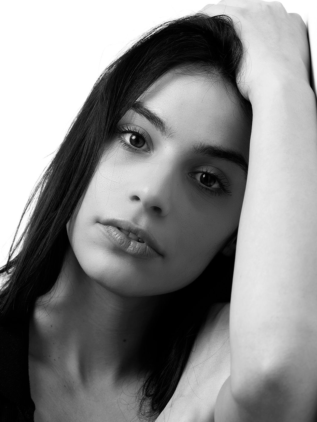 Black and white portrait of a young woman with dark hair, posing with hand raised near her head. Gombó Viola Lotti