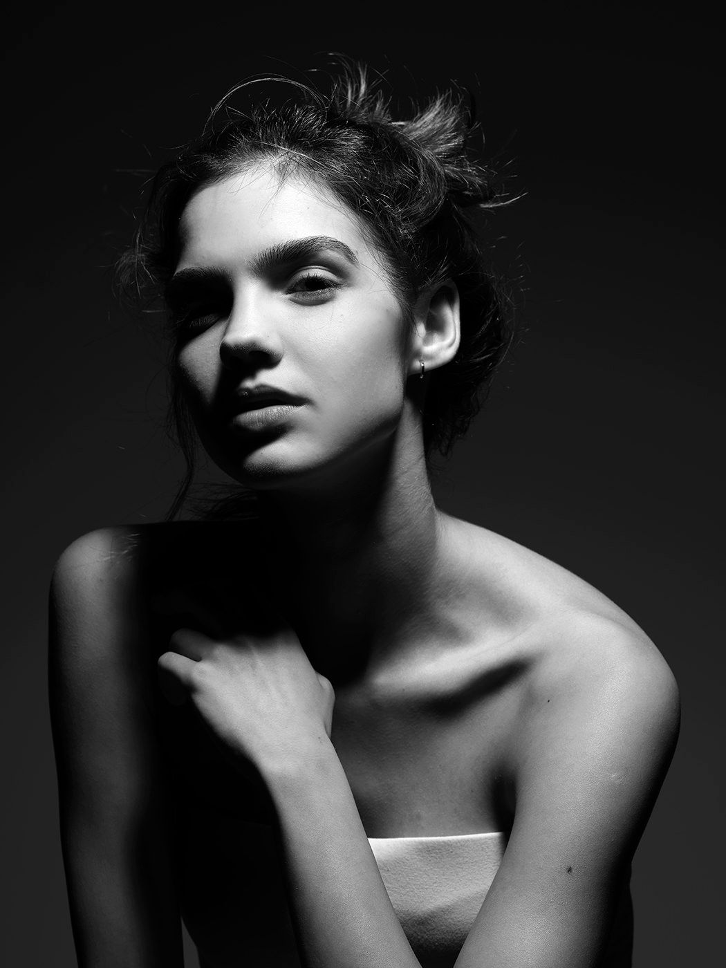 Black and white portrait of a young woman with upswept hair, dramatic lighting highlighting her elegant features.
