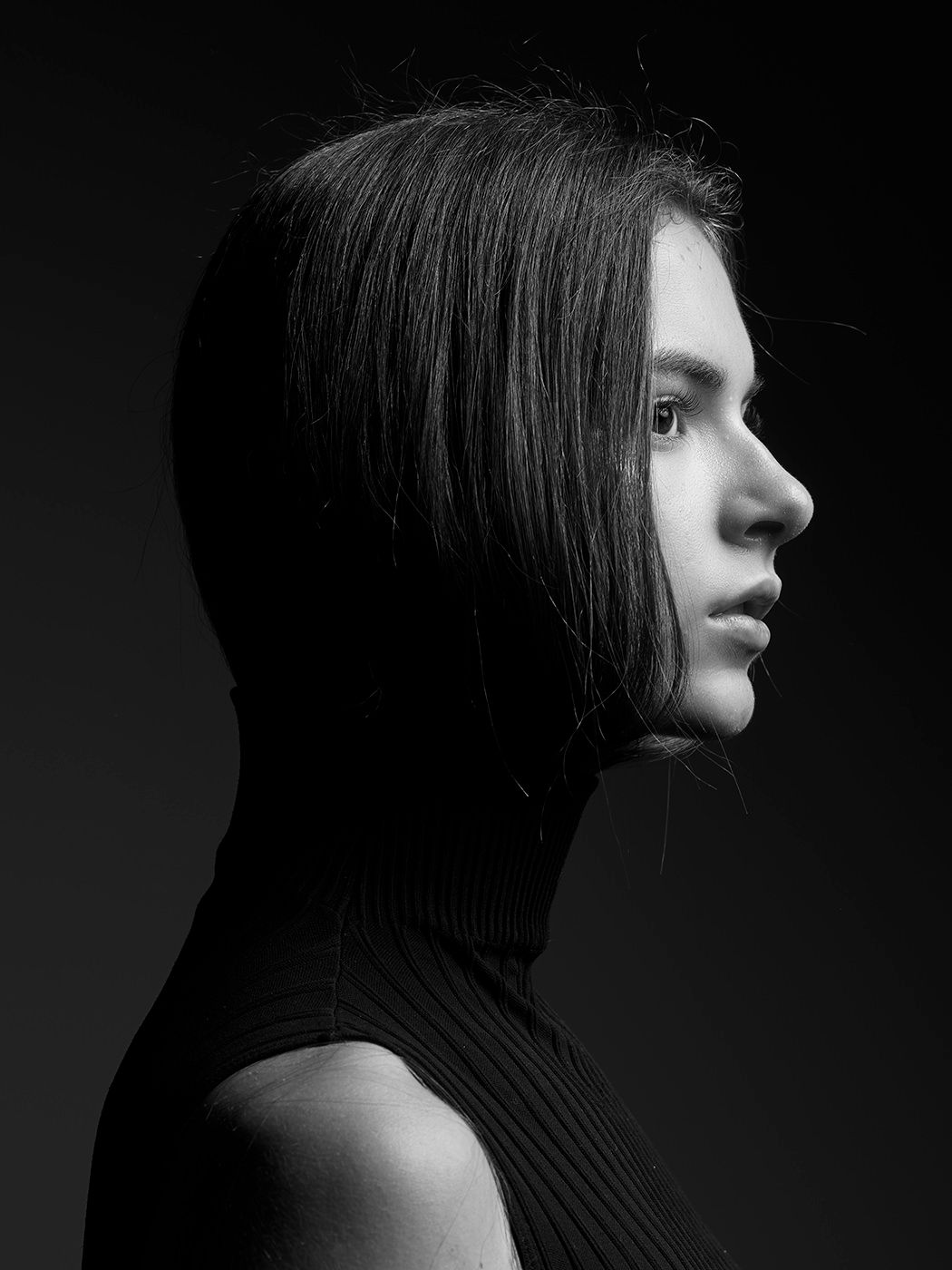 Black and white profile portrait of a young woman with straight dark hair wearing a ribbed turtleneck top.