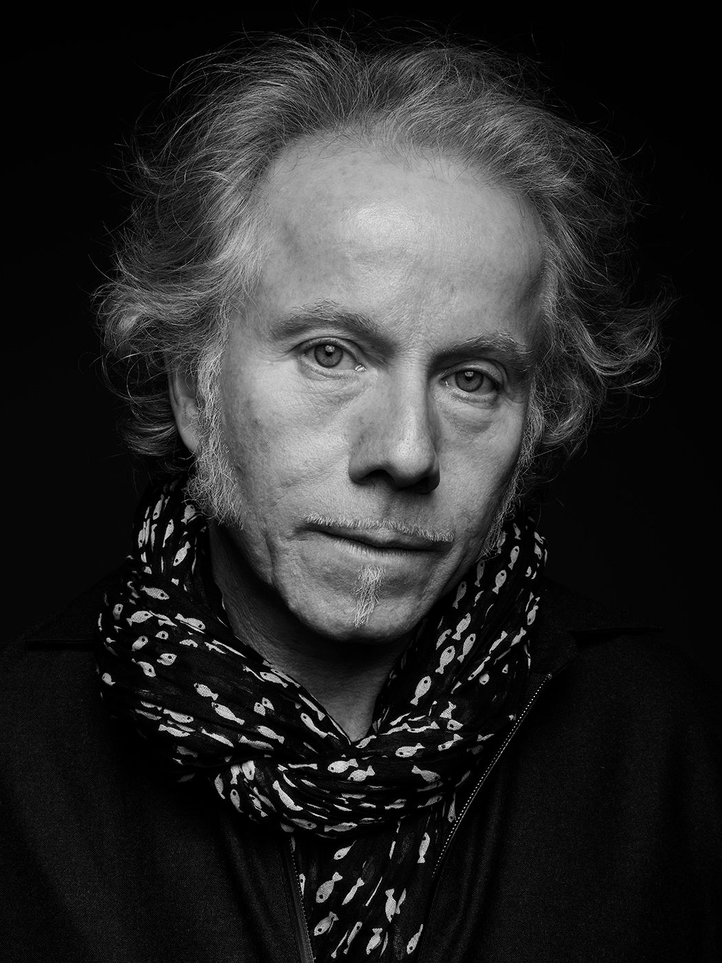 Black and white portrait of a middle-aged man with wavy gray hair wearing a patterned scarf. Kárpáti Dódi