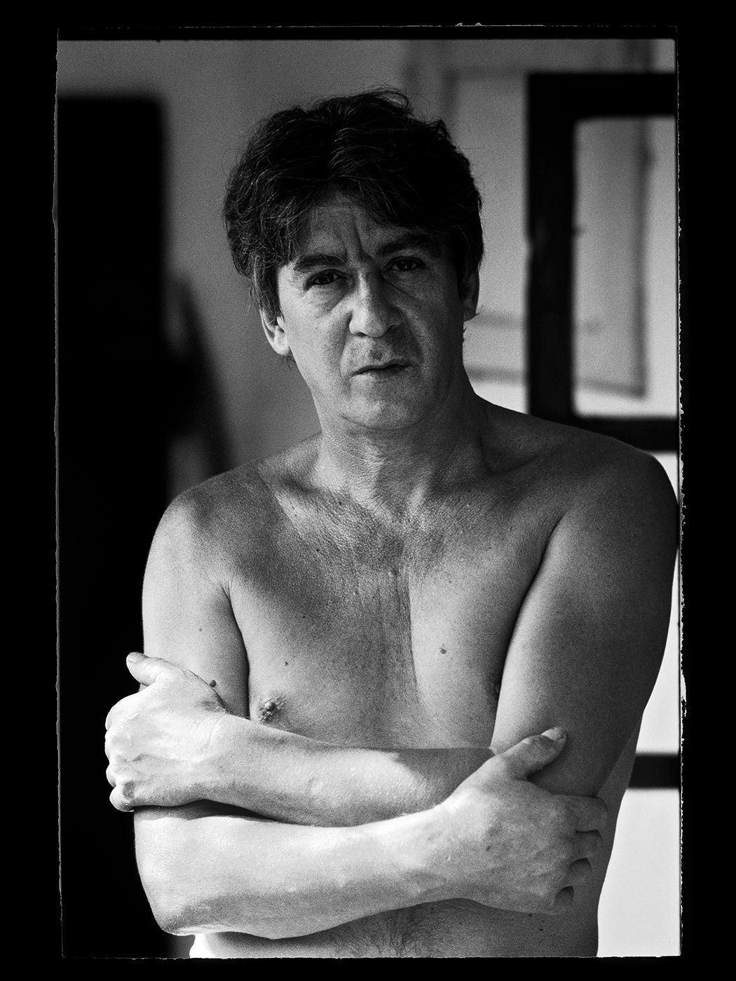 Black and white portrait of a shirtless middle-aged man with arms crossed, looking directly at camera. Cseh Tamás