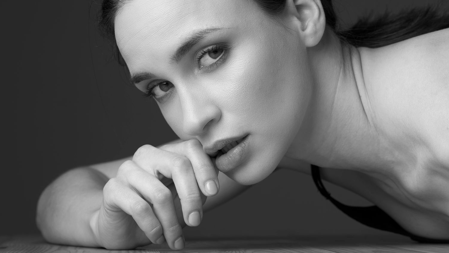 Black and white portrait of a pensive young woman resting her chin on her hand, gazing thoughtfully at the camera. Törőcsik Franciska