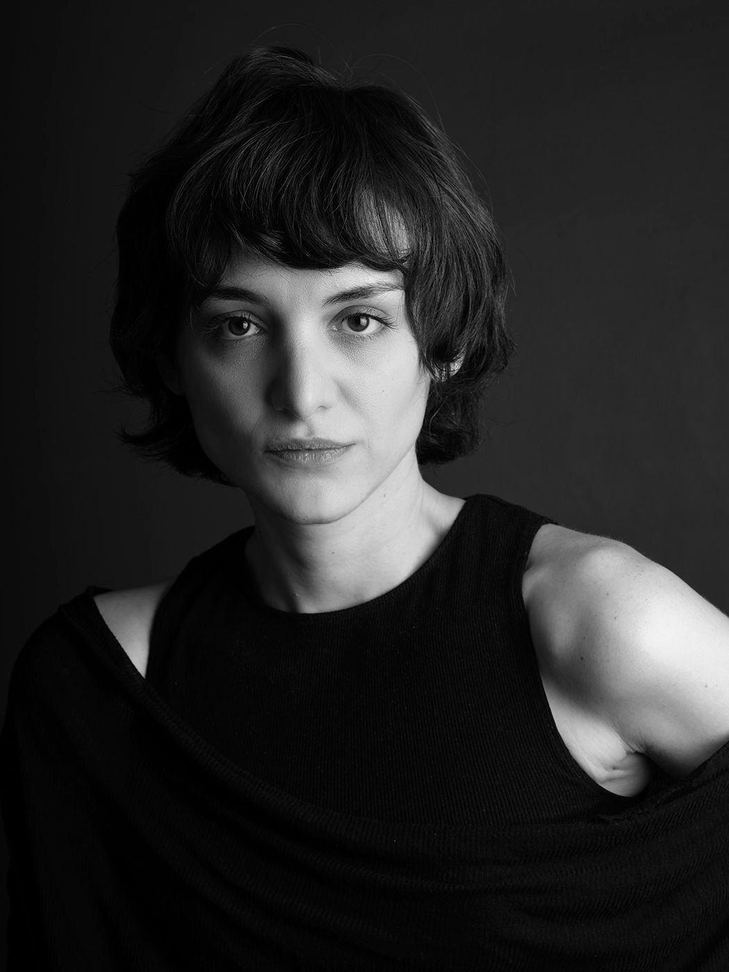 Black and white portrait of a young woman with short dark hair wearing a sleeveless black top.