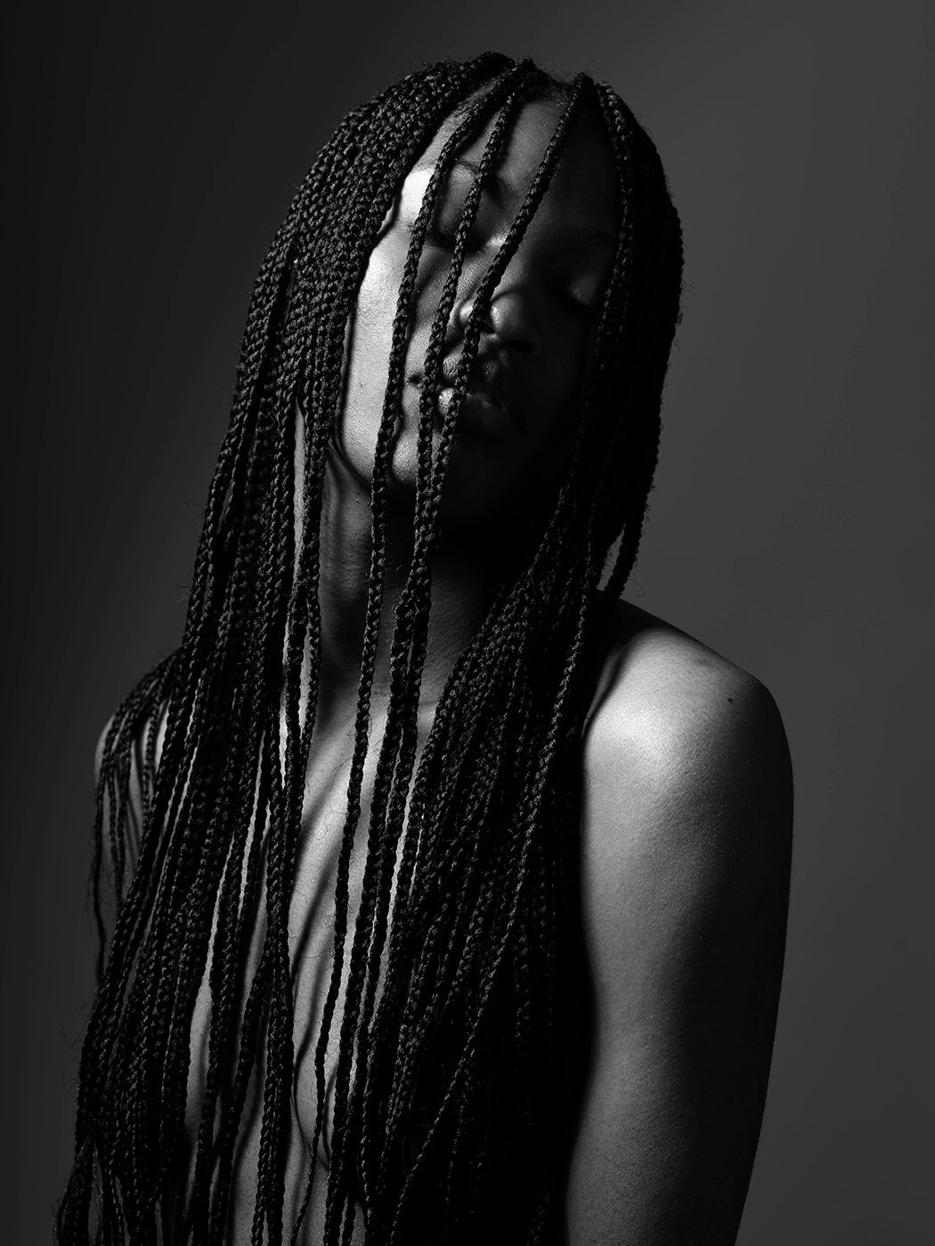 Black and white portrait of a woman with long box braids cascading over her face and shoulders.