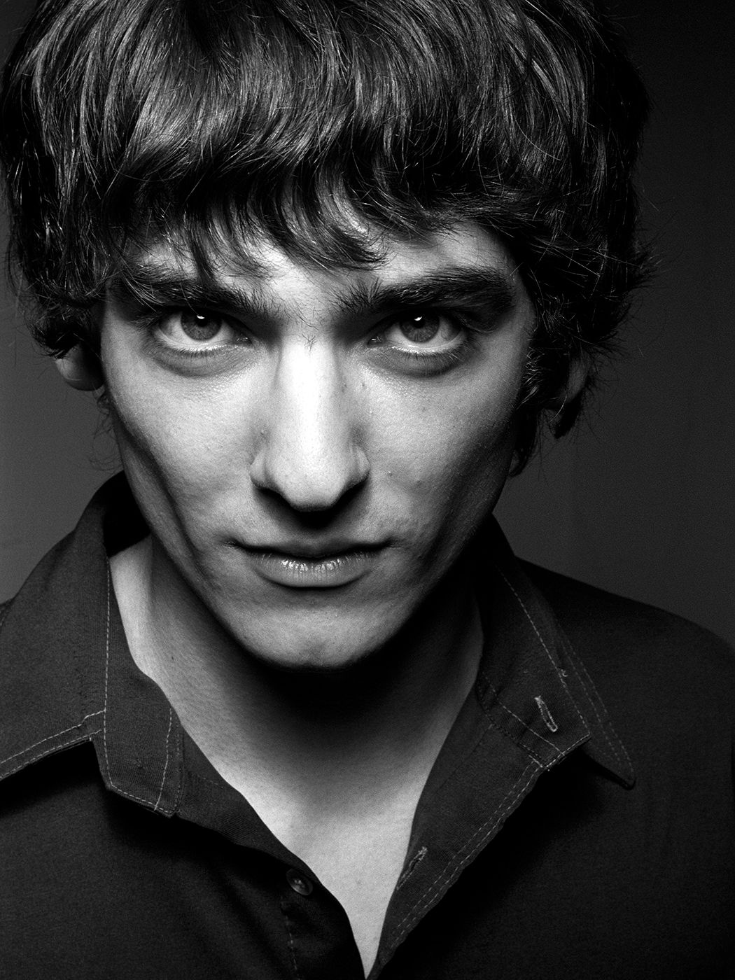 Black and white portrait of a young man with dark eyes and bangs, wearing a dark shirt, intense gaze. Fogarasi László, Yonderboi