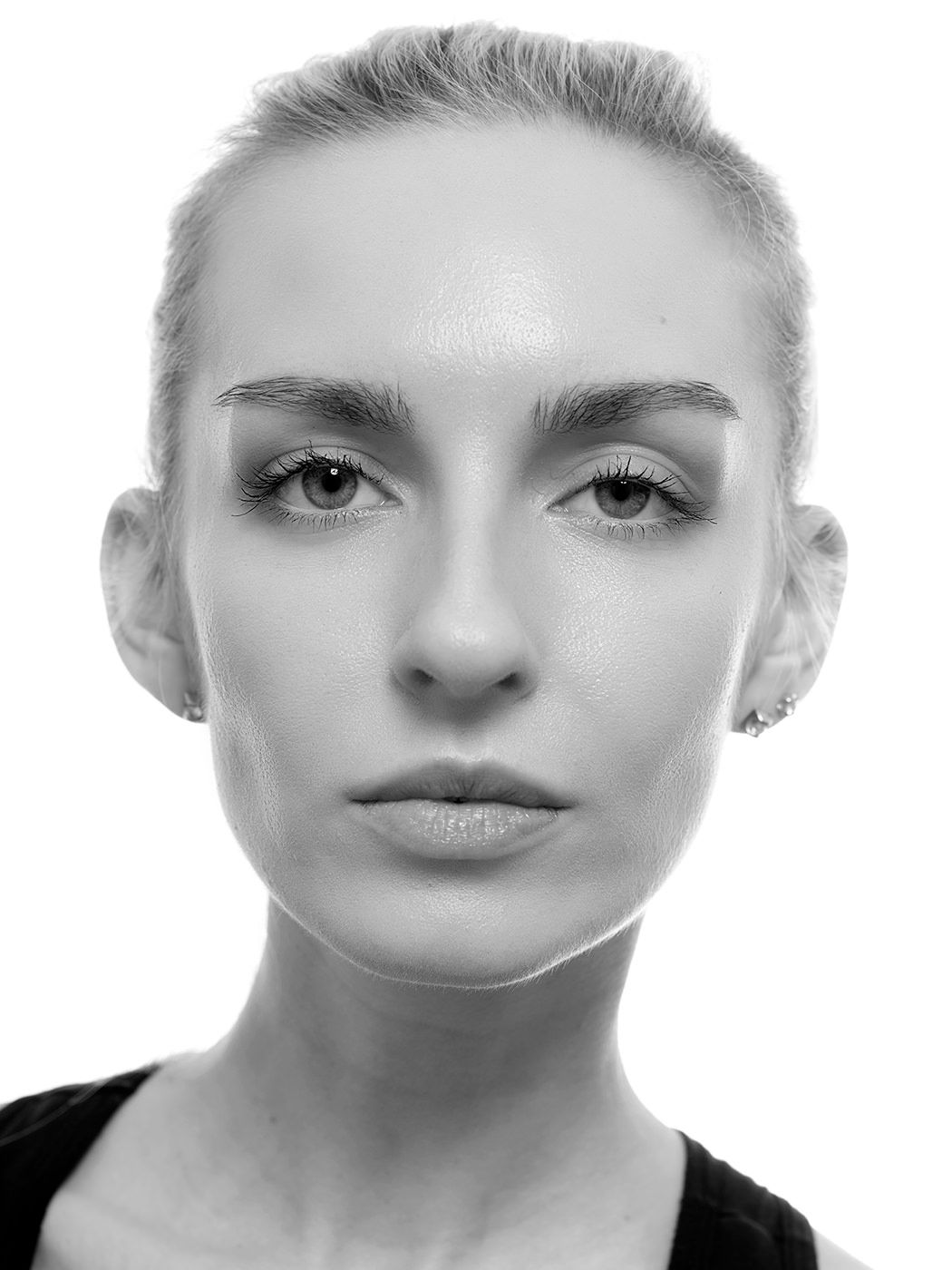 Black and white front-facing portrait of a young woman with very short blonde hair and defined eyebrows.