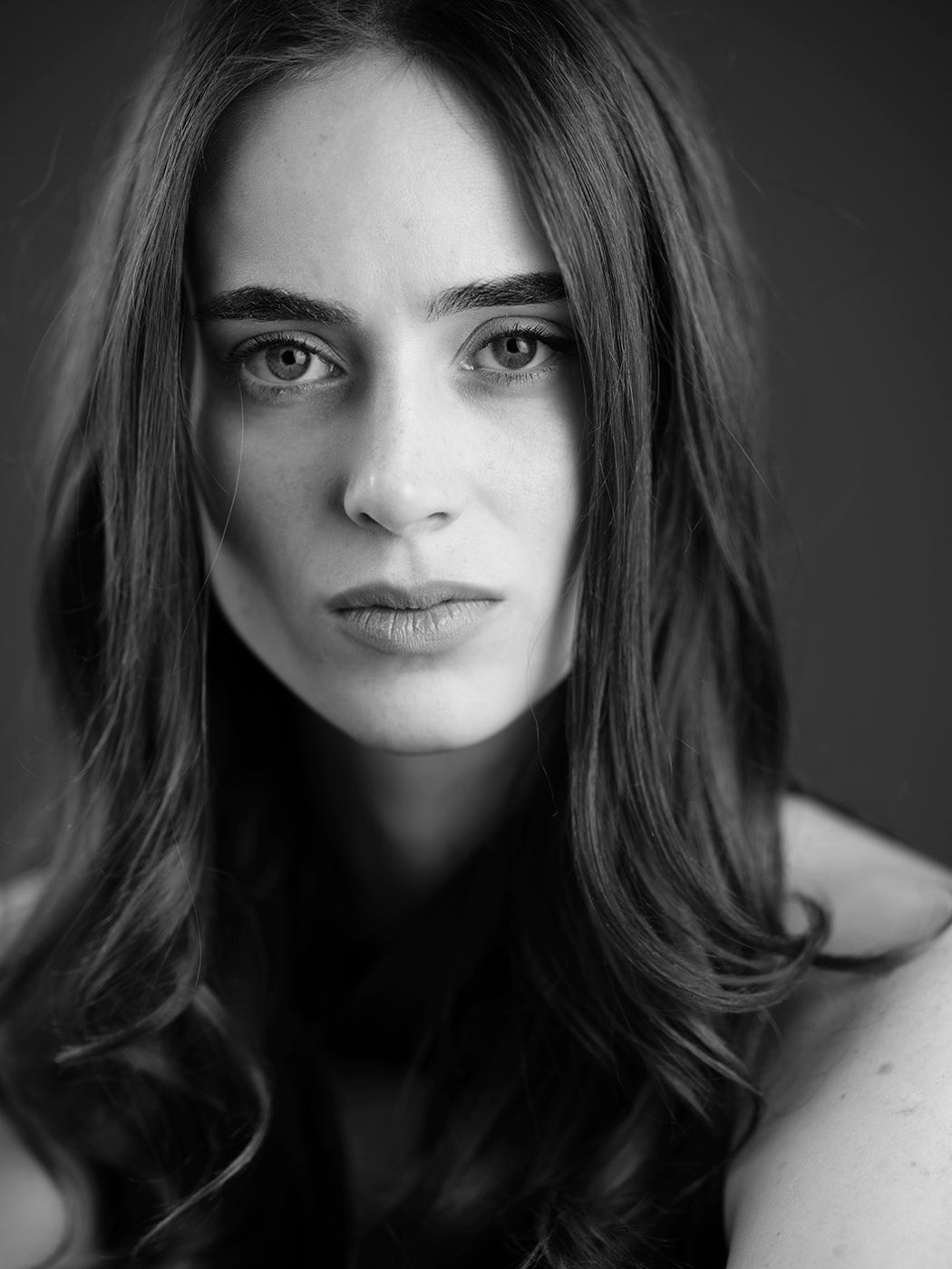 Black and white close-up portrait of a young brunette woman with intense eyes and long hair.