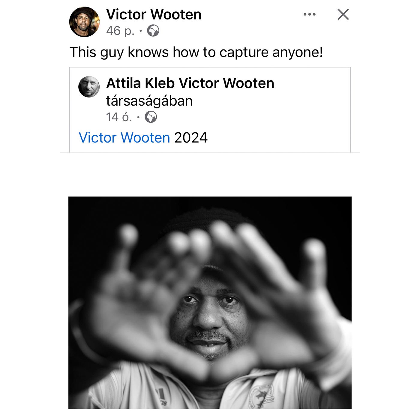 Victor Wooten framing his smiling face with both hands forming a heart shape in a black and white portrait photo.