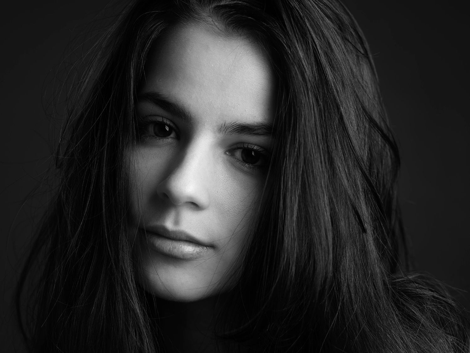 Black and white portrait of a young woman with long dark hair and a contemplative expression. Orbay Lilla, singer