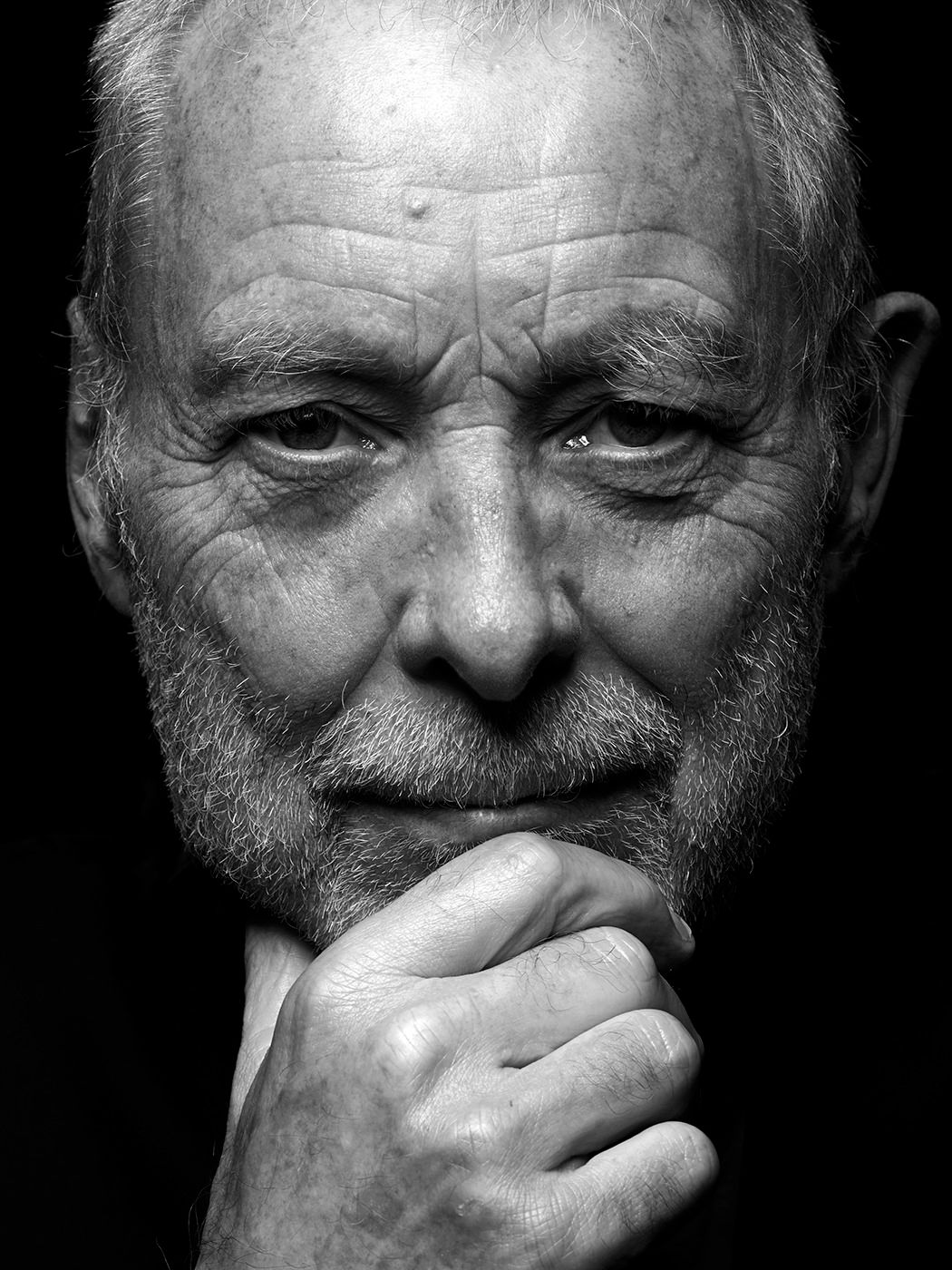 Close-up black and white portrait of an elderly man with a beard resting his chin on his fist. Dave Holland