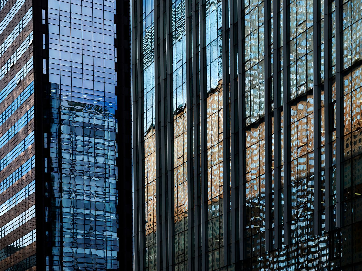 Glass skyscrapers reflecting urban buildings in blue and gold tones, showcasing modern city architecture.