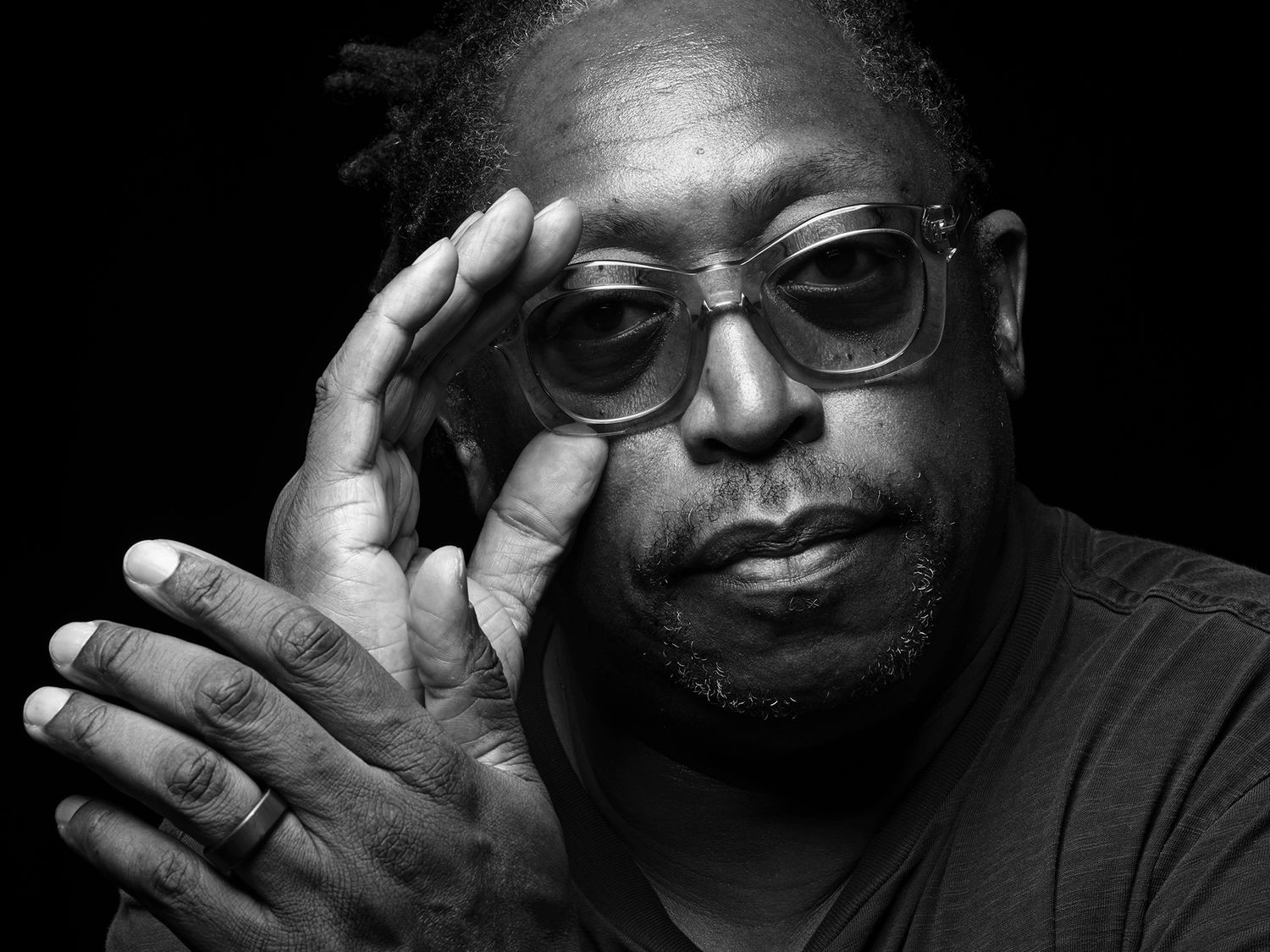 Black and white portrait of a man with glasses and a beard, resting his hand thoughtfully against his face. Darryl Jones