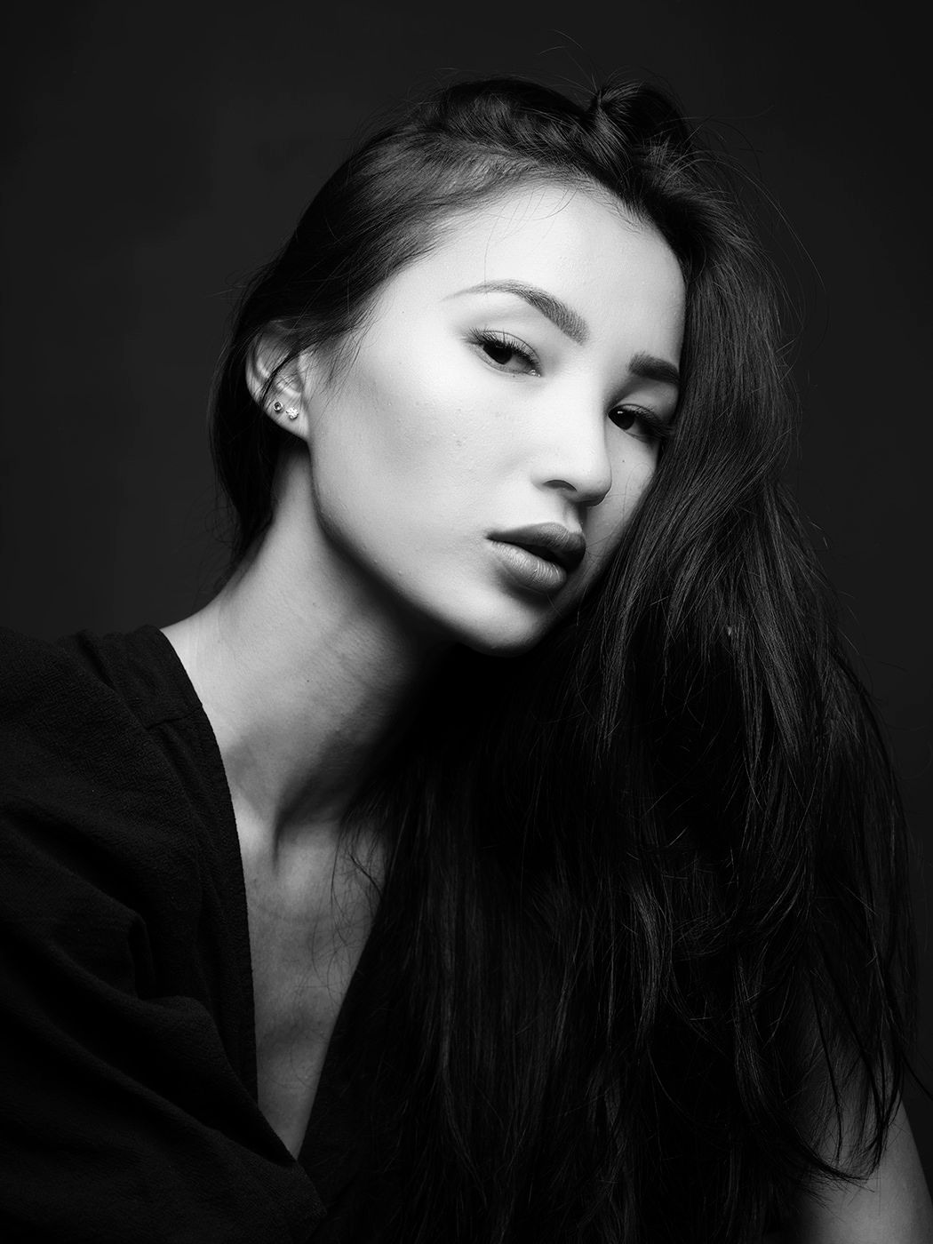 Black and white portrait of a young woman with long dark hair posing against a dark background.