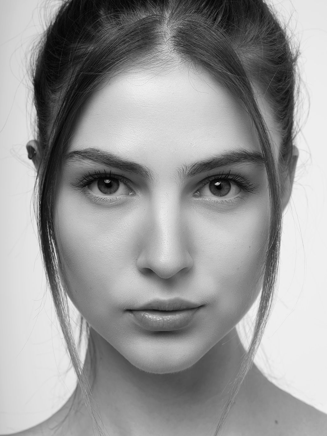 Close-up black and white portrait of a young woman with dark hair and striking facial features.
