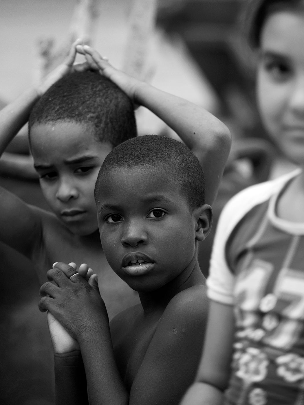 Black and white photo of two young boys looking at camera, with a girl visible in the background.