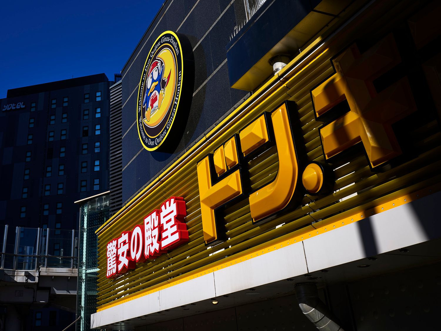 Don Quijote discount store illuminated yellow and black sign in Japan at dusk.