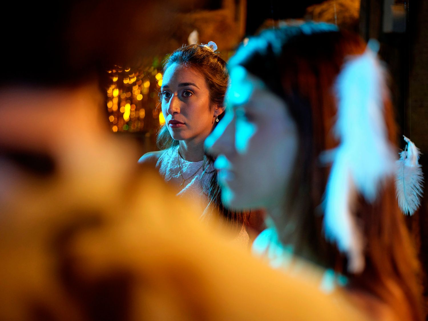 People in costumes at a dimly lit party with blue and orange lighting.