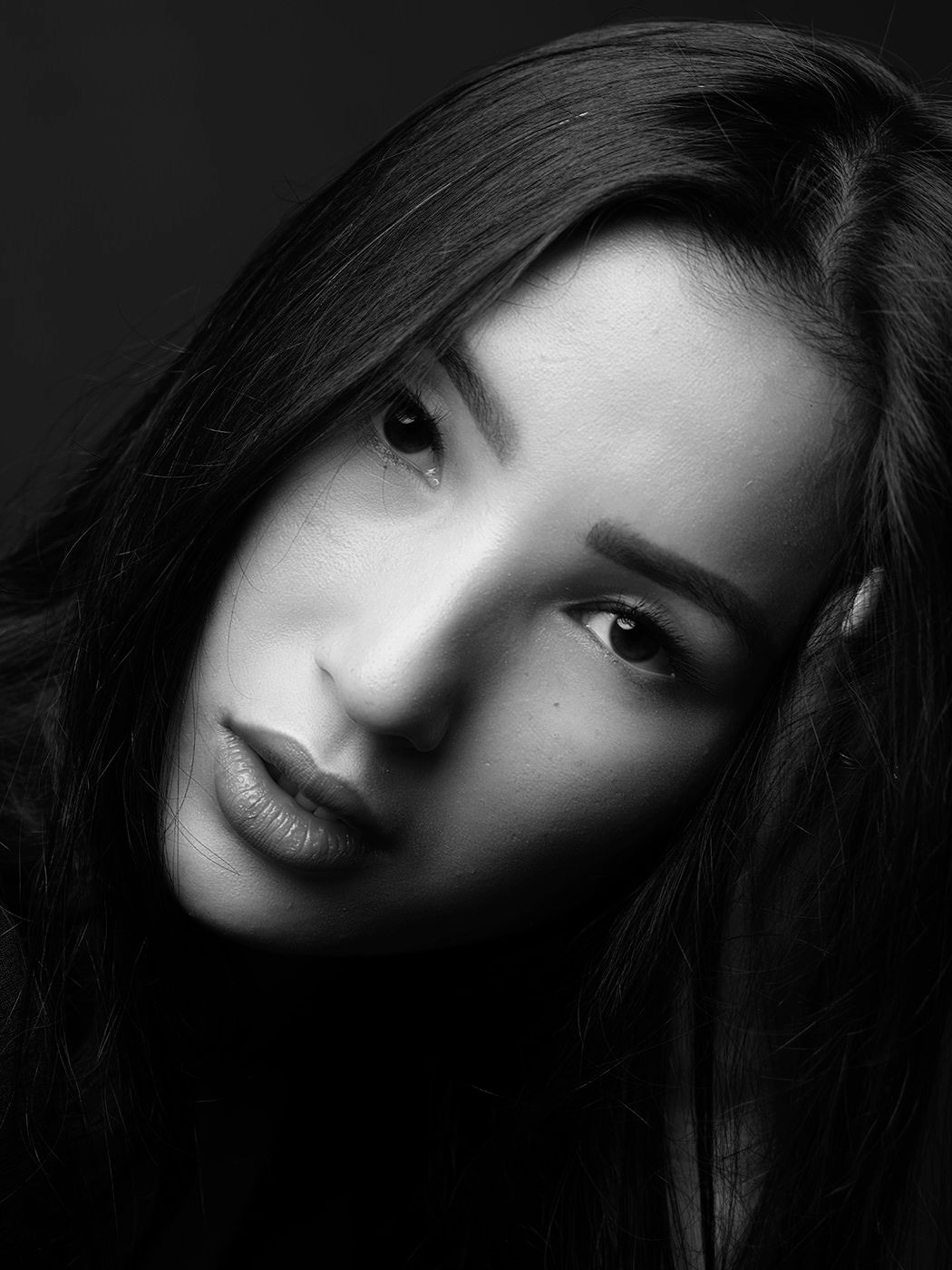 Black and white portrait of a young woman with long dark hair, gazing intensely at the camera.