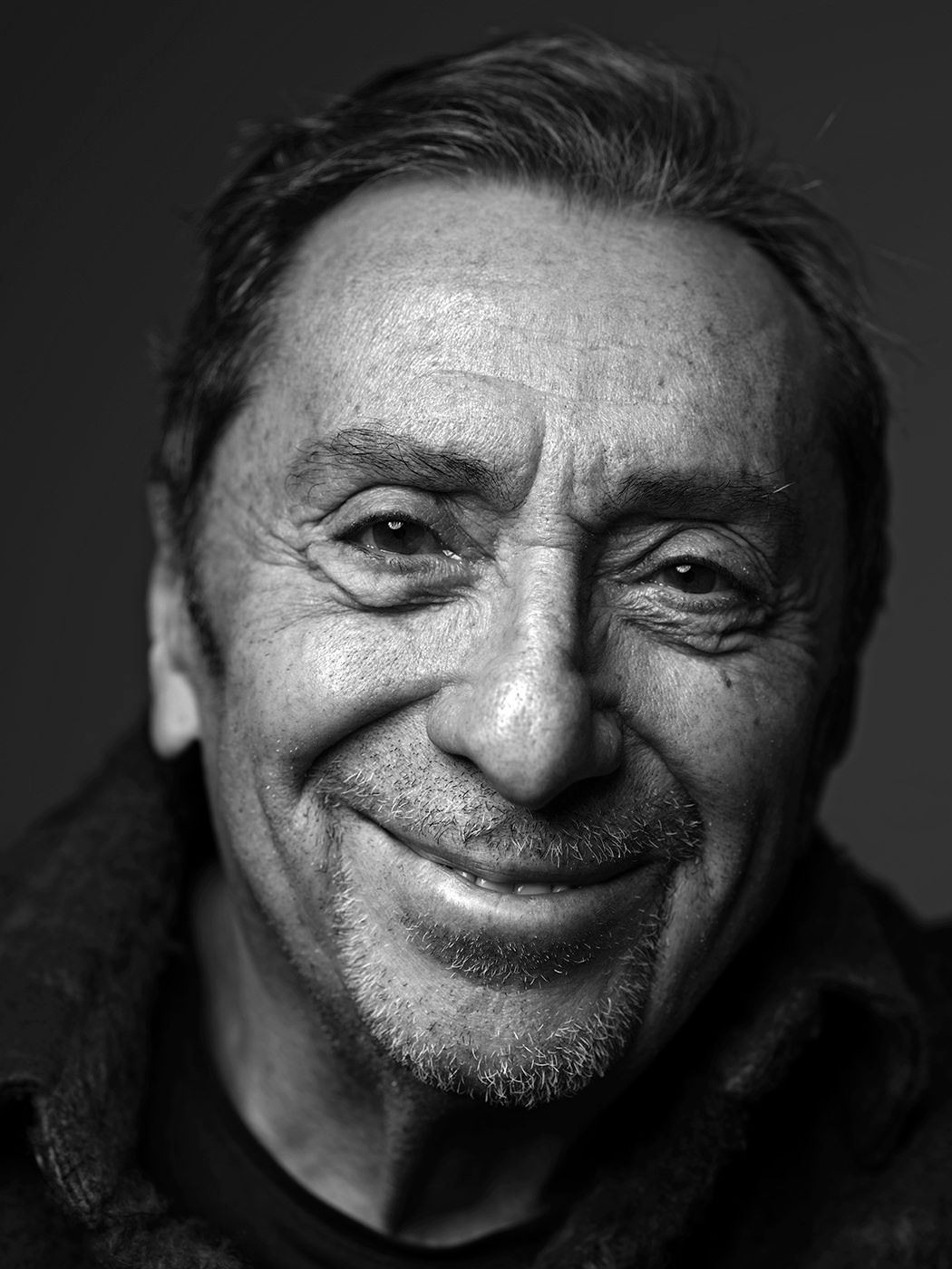 Black and white portrait of a smiling older man with expressive features and short gray hair. Kőszegi Imre