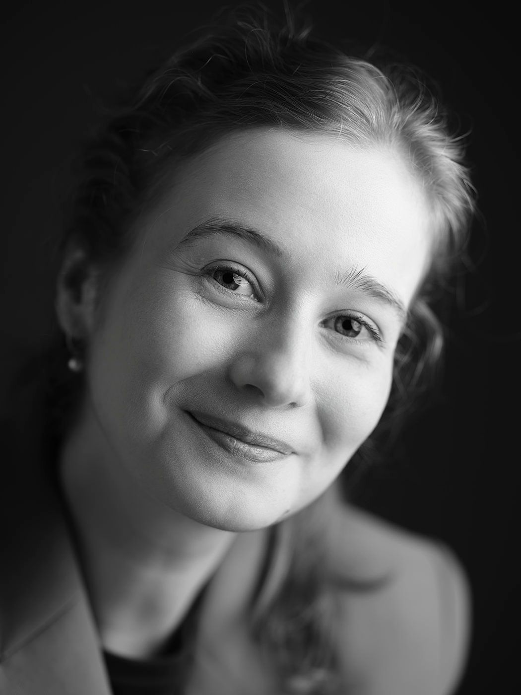Elegant black and white portrait of a young woman with soft features smiling gently at the camera.
