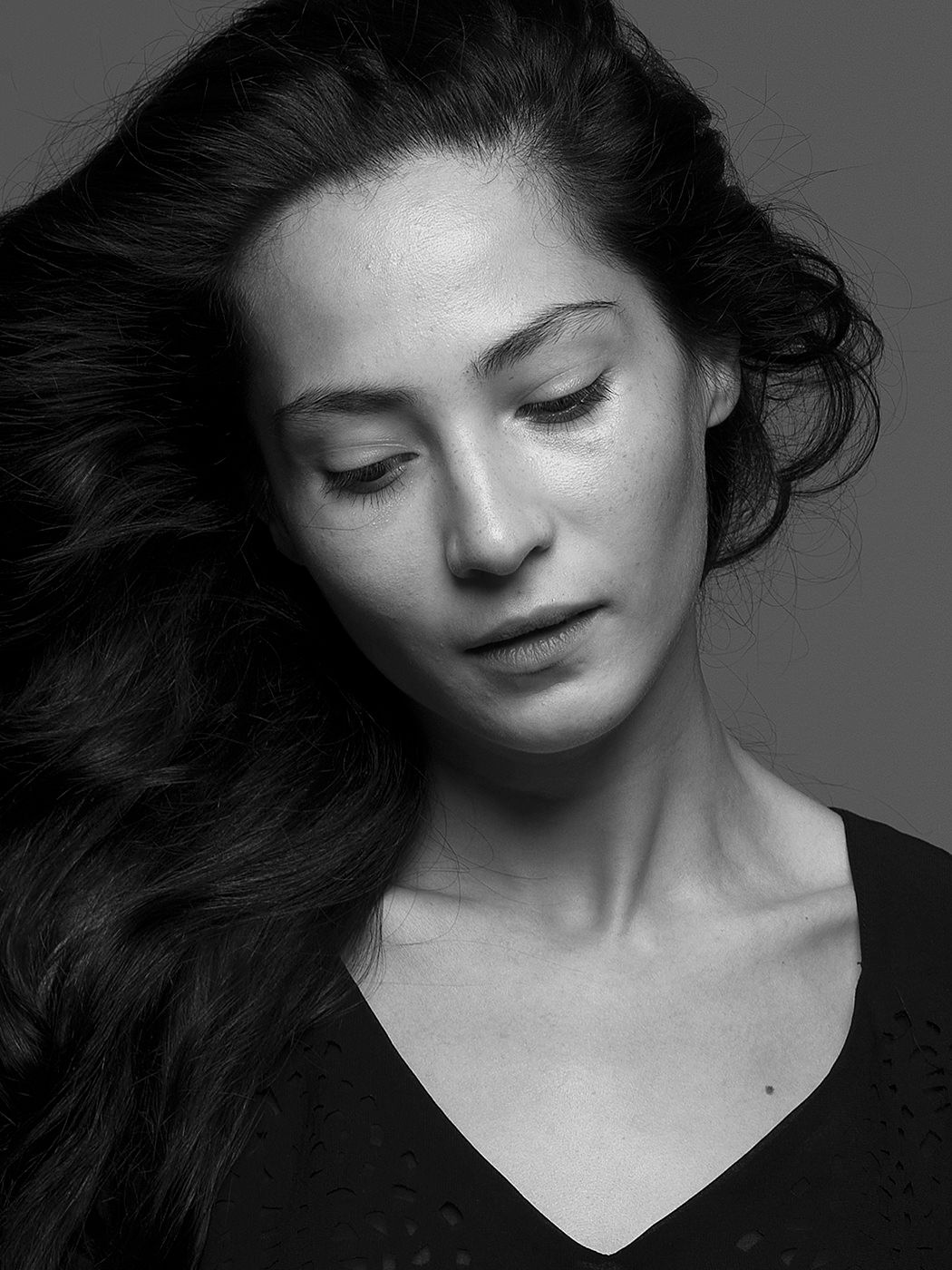 Black and white artistic portrait of a woman with long dark flowing hair, eyes gently closed.
