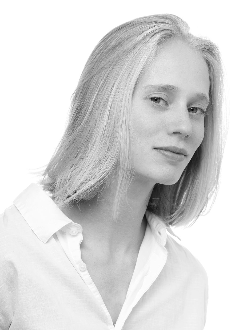Black and white portrait of a young blonde woman in a white collared shirt against a light background.