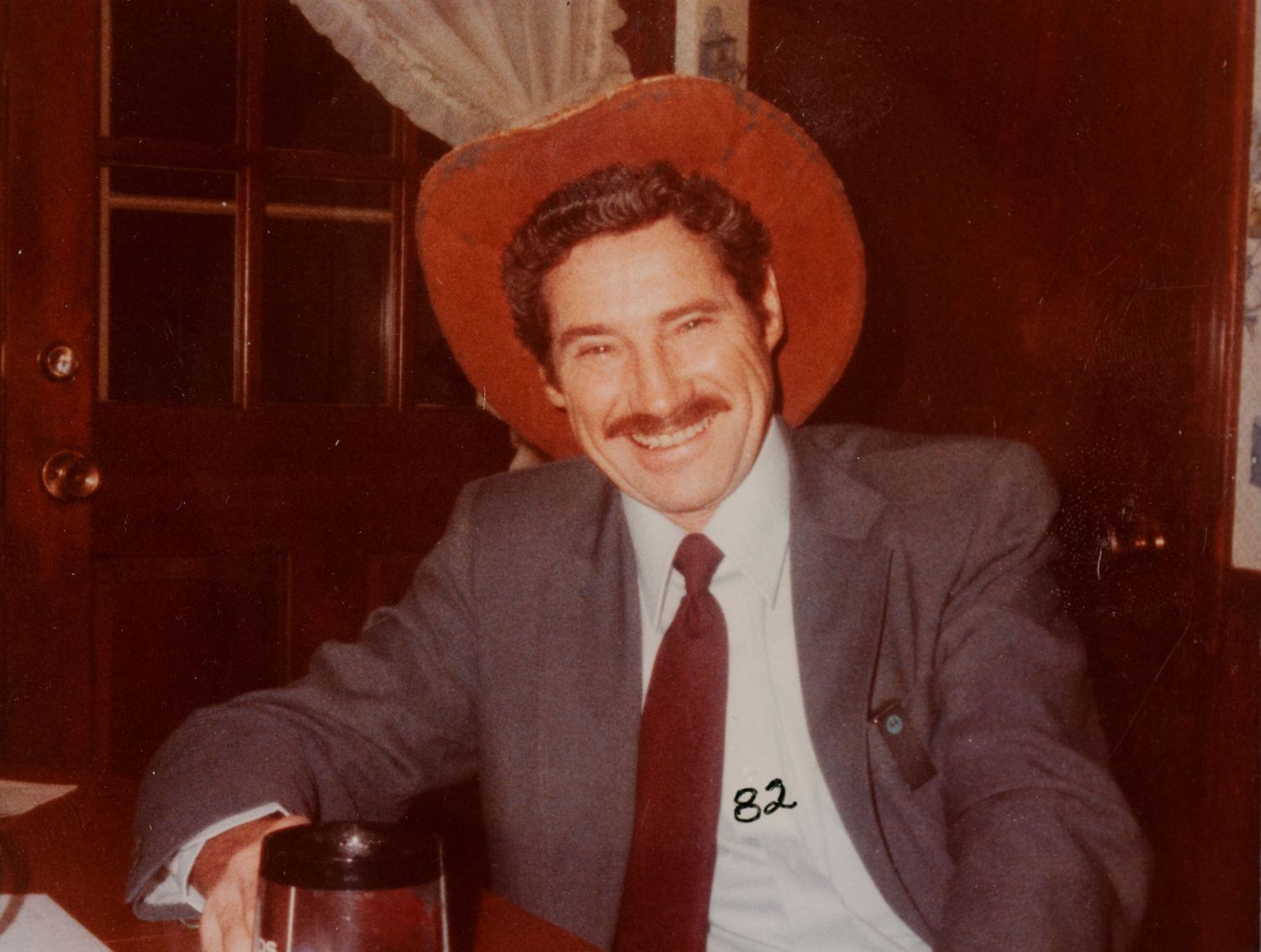 Vintage portrait of a man in a red cowboy hat before digital photo restoration.