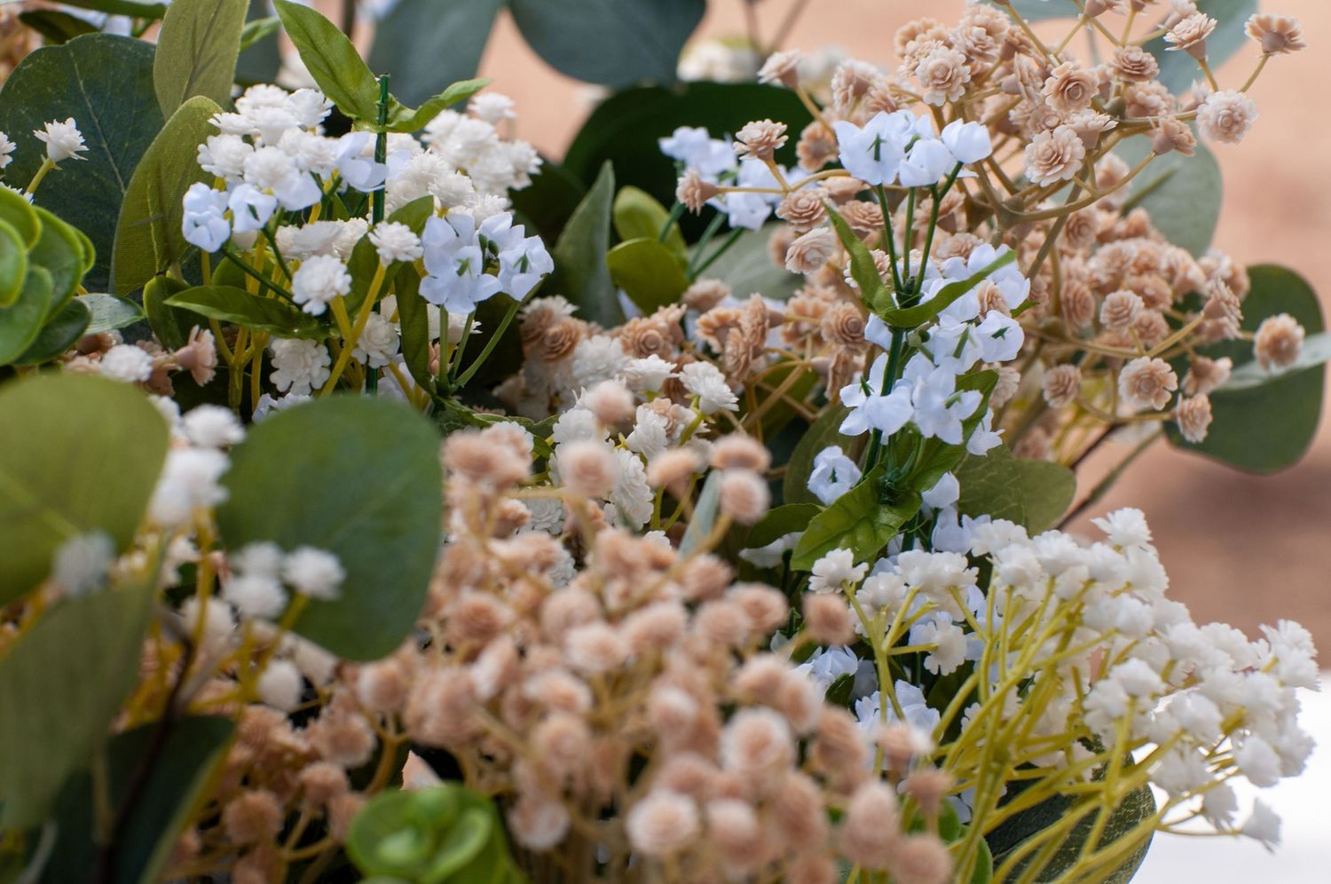 Close-up of delicate white and beige wildflowers with green eucalyptus leaves arrangement.