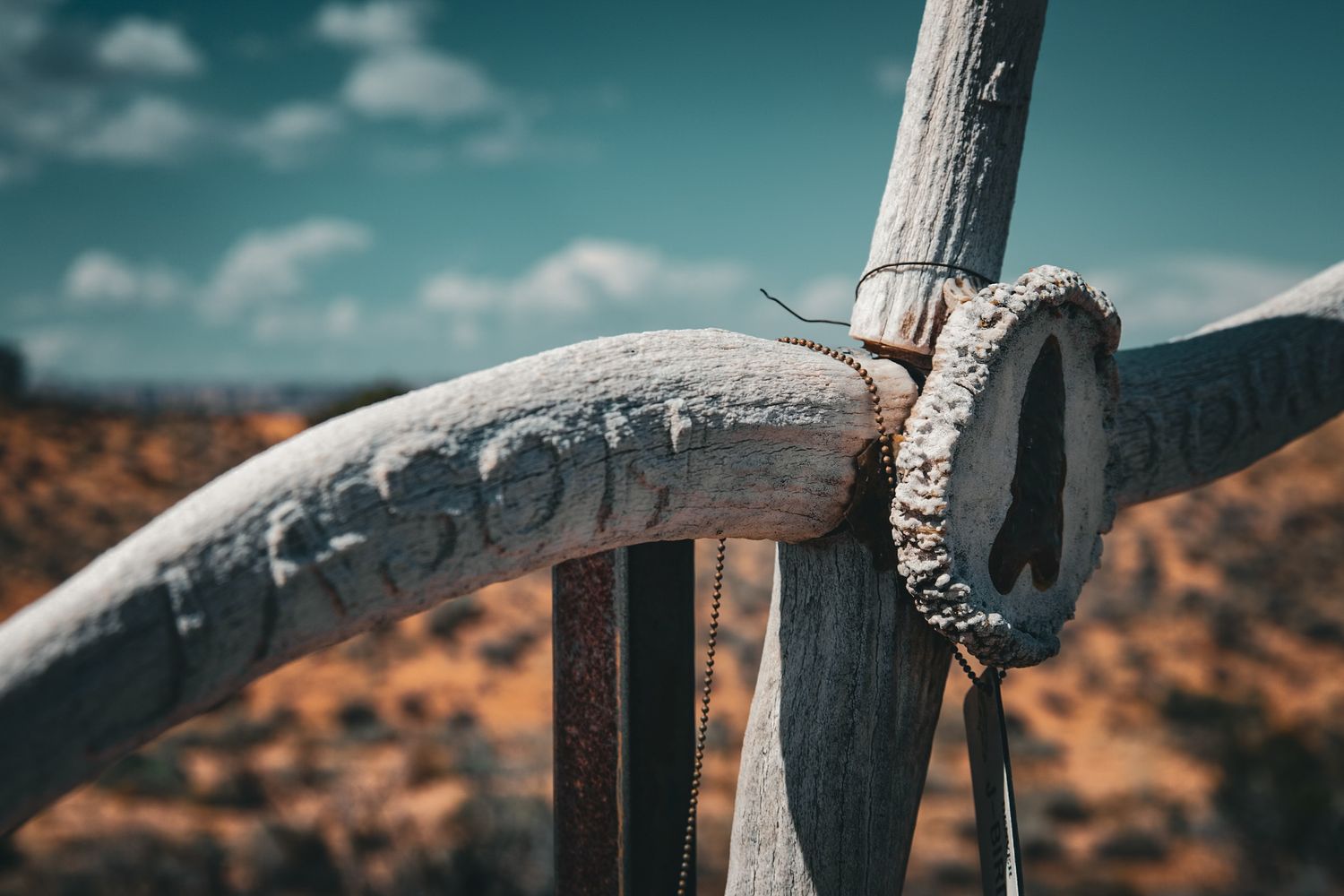 Detailed view of rustic white painted wooden cross joint secured with rope in desert setting.