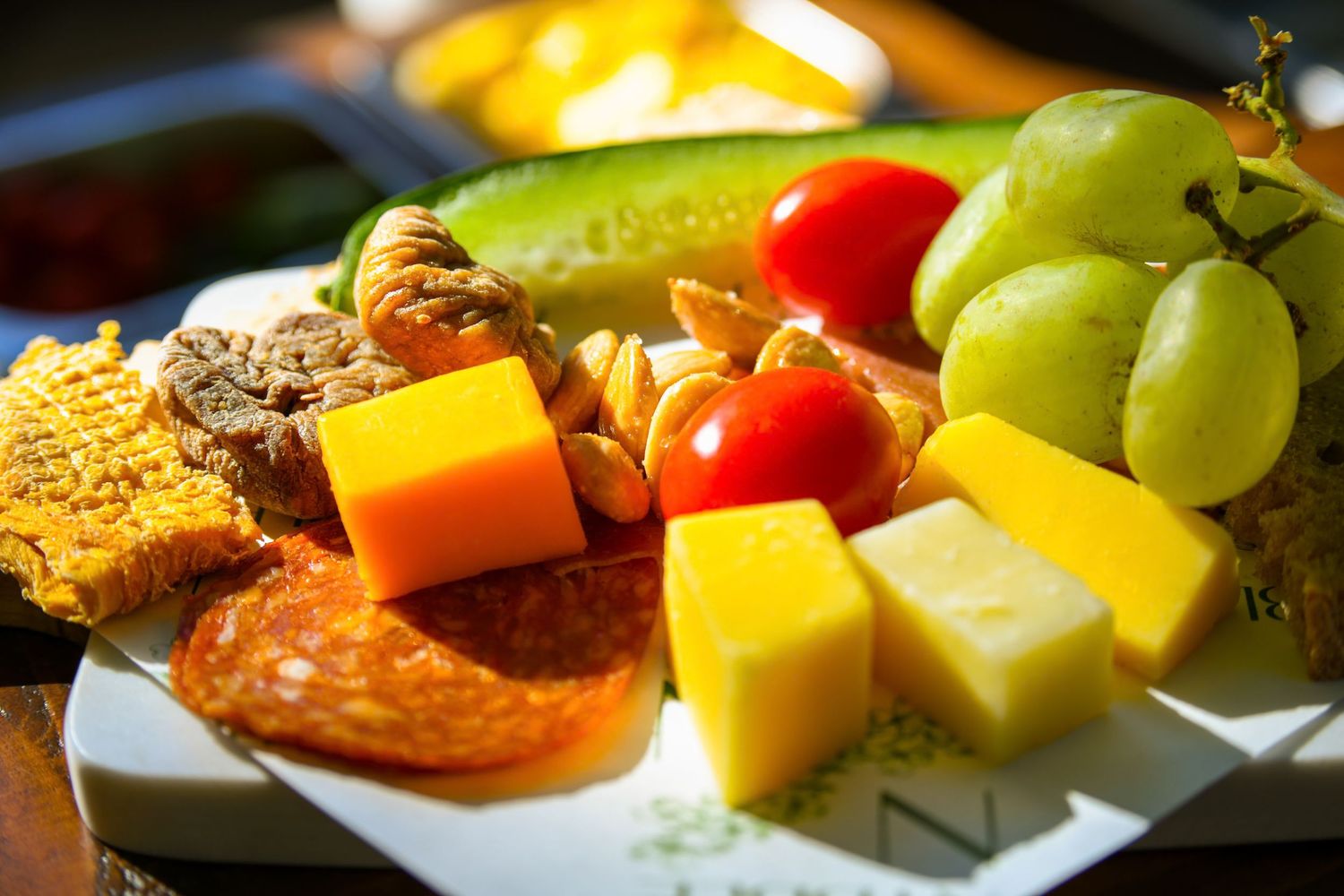 Colorful charcuterie plate with cheese cubes, salami, grapes, tomatoes, and mixed snacks.